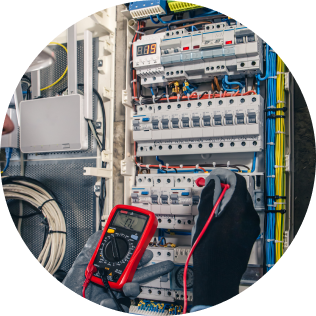 Serwisant elektryczny w rękawicach ochronnych mierzy parametry elektryczne za pomocą profesjonalnego urządzenia pomiarowego.