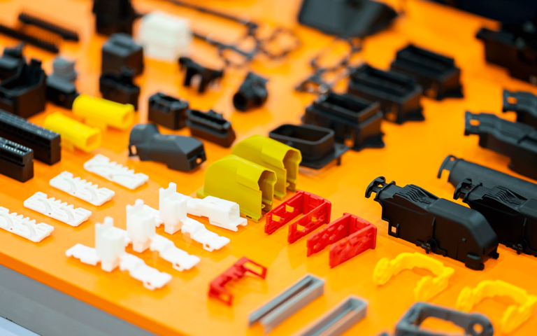 Próbki elementów wykonanych metodą wtrysku tworzyw sztucznych. Widoczne są różne kolory i tekstury materiału.