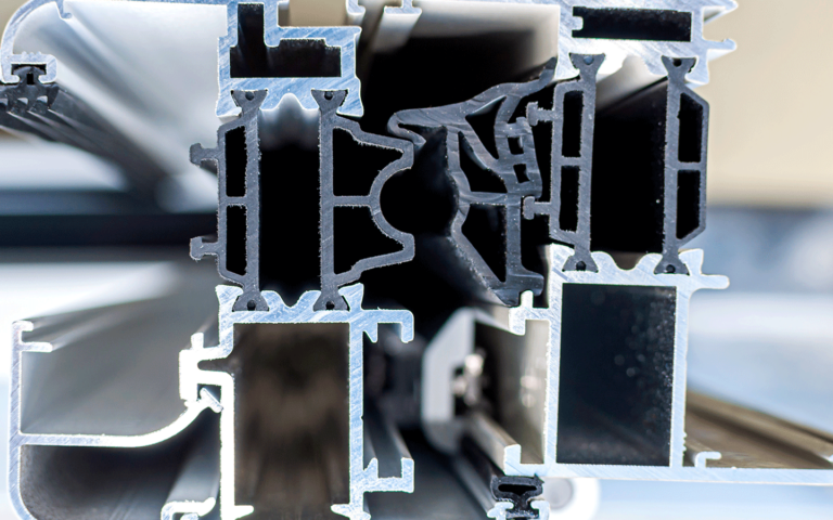 Zbliżenie na przekrój poprzeczny profilu aluminiowego, ukazujące jego wewnętrzną strukturę z komorami i uszczelkami.