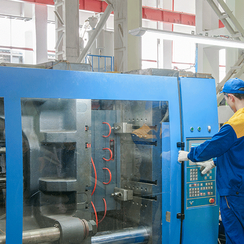 Fragment linii produkcyjnej. Osoba w odzieży ochronnej pracuje przy urządzeniach.