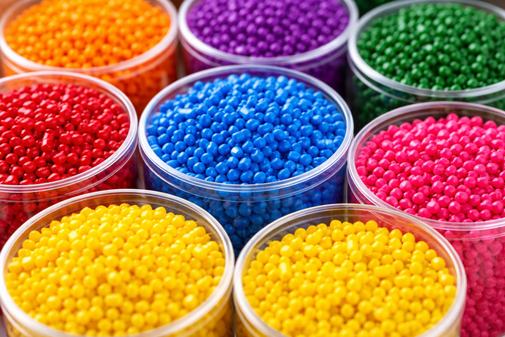 Zbliżenie na granulki tworzywa sztucznego różnych kolorów w pojemnikach