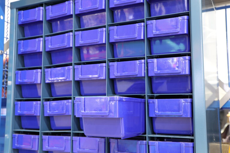 Plastikowe pudełka na narzędzia i elementy, na regale.